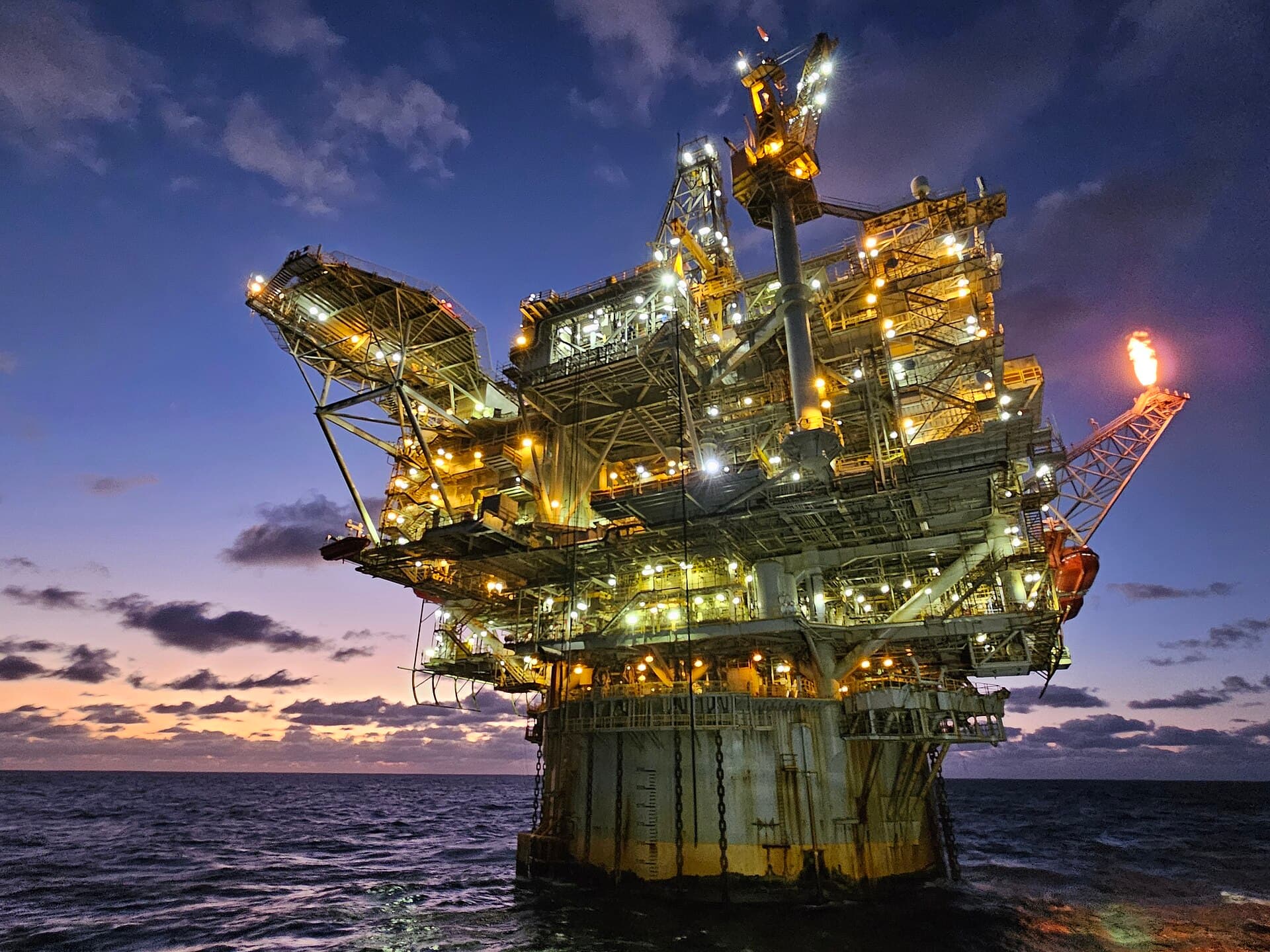 Offshore oil production platform lit at dusk